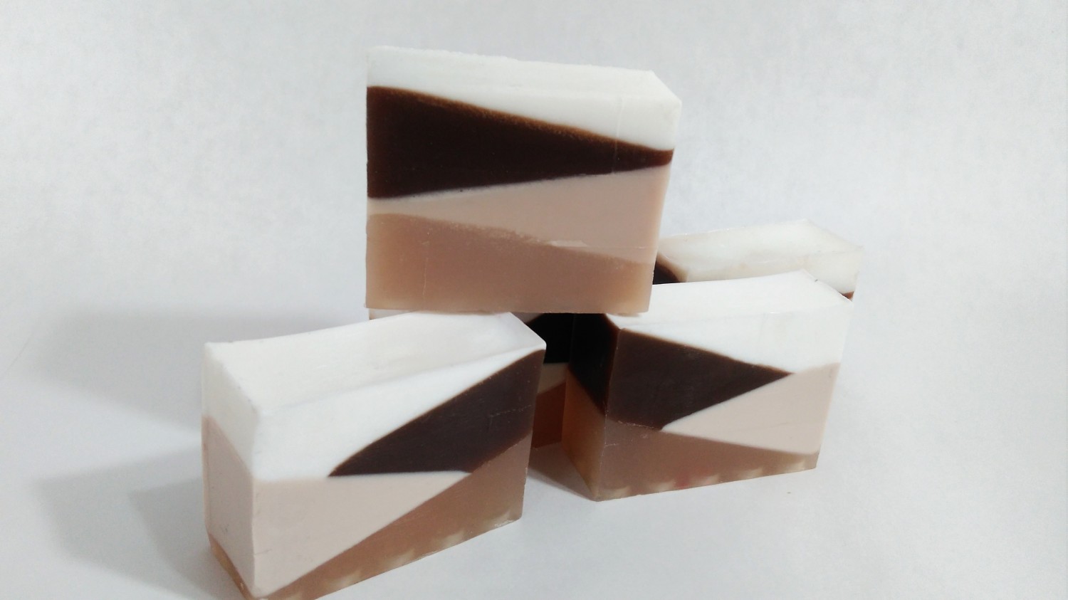 Caramel soap in three pieces in shades of brown stacked on top of each other on a white background.